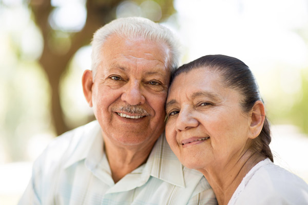 Smiling older couple leaning cheek to cheek.