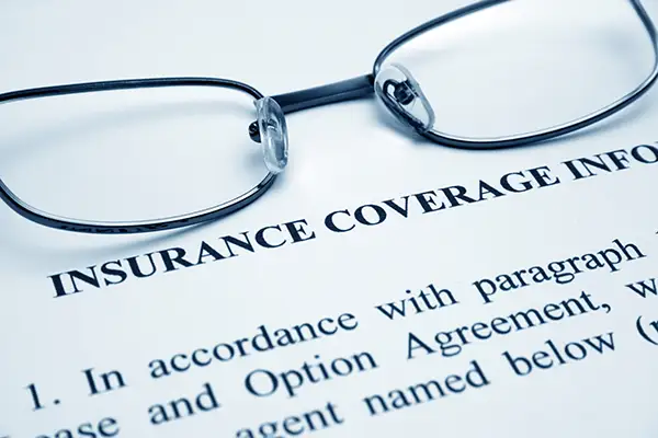 A pair of glasses sitting on top of a large piece of paper explaining insurance coverage information.